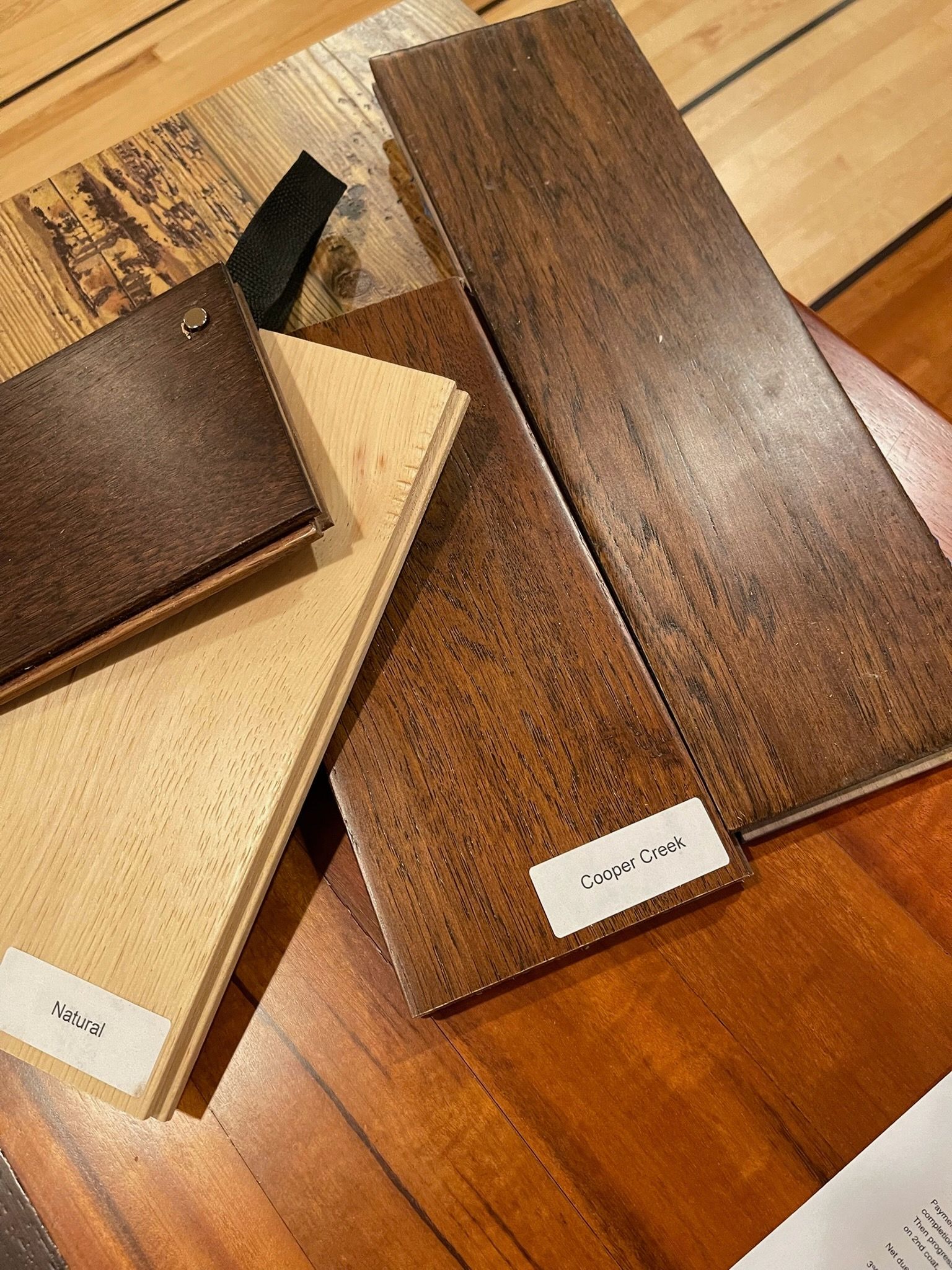 A collection of wood flooring samples in various brown and tan shades, arranged on a wooden surface.