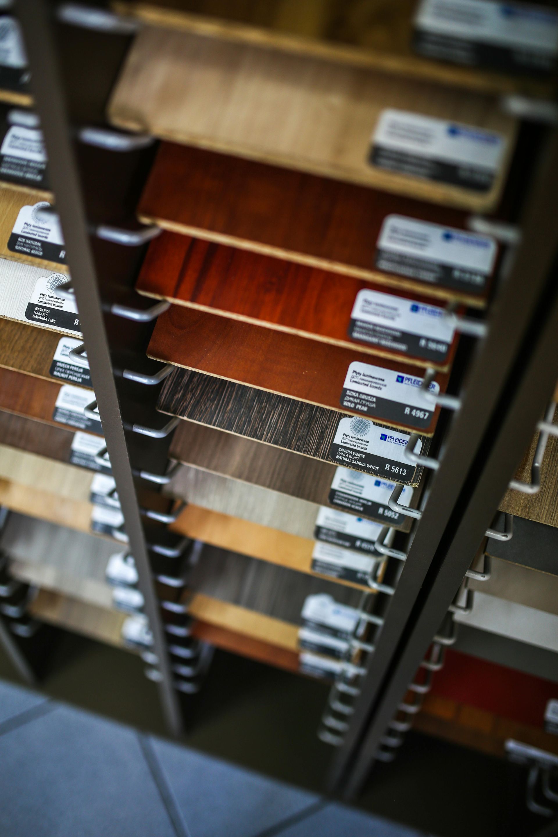 A display rack holding various wood and laminate flooring samples in a showroom, viewed from an angled perspective.