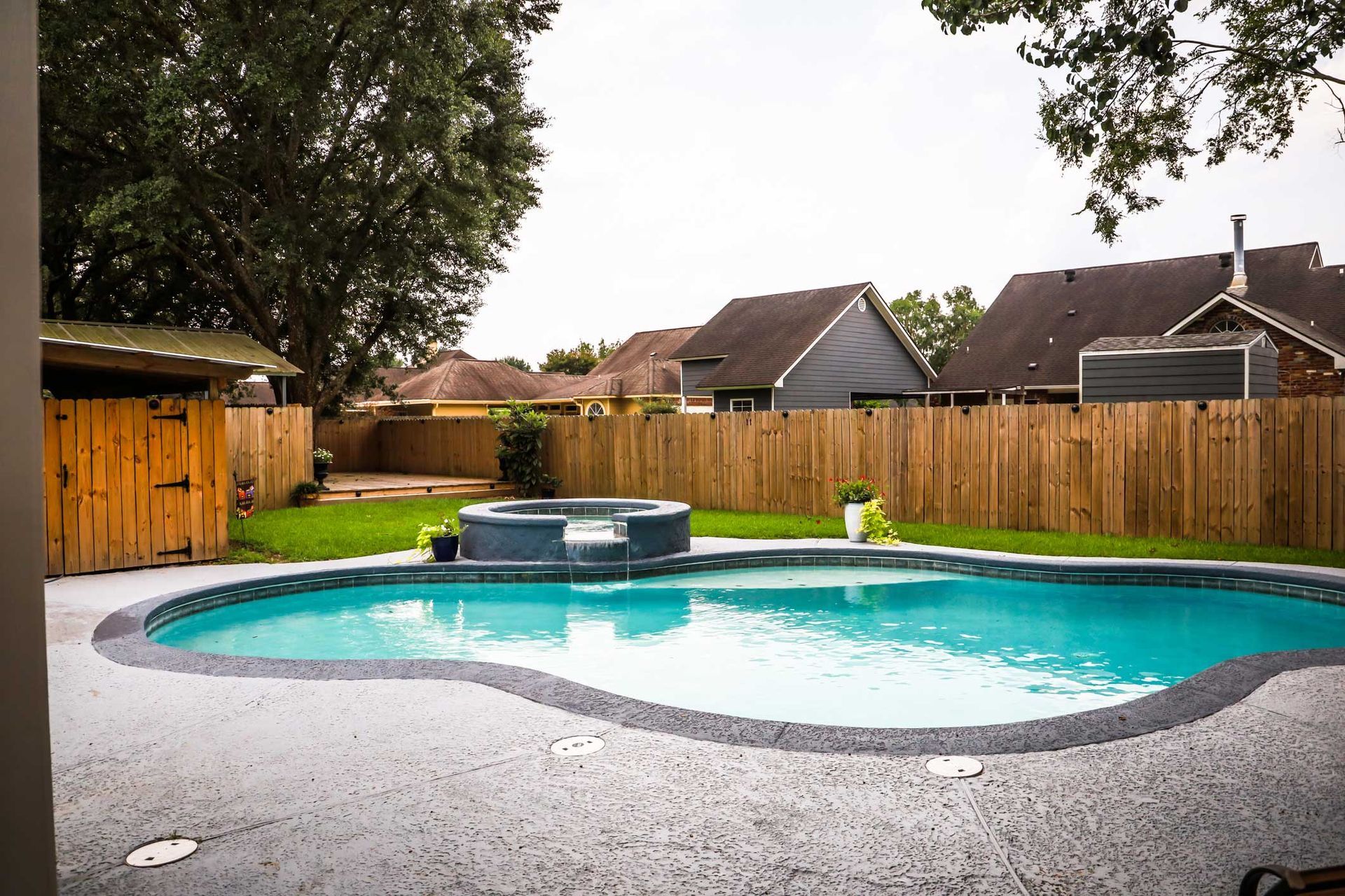 A large swimming pool with a hot tub in the backyard of a house.