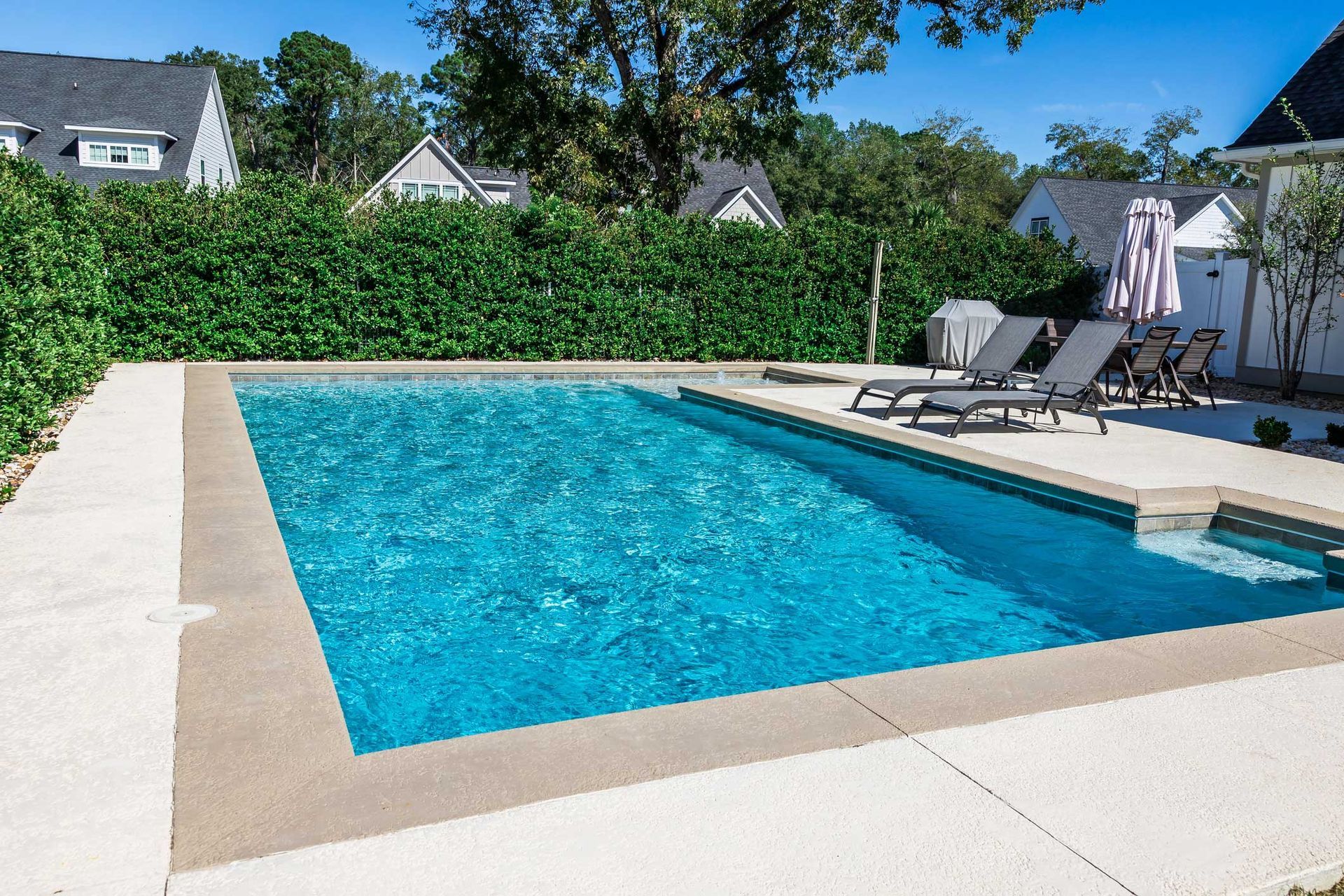 A large swimming pool surrounded by chairs and a fence