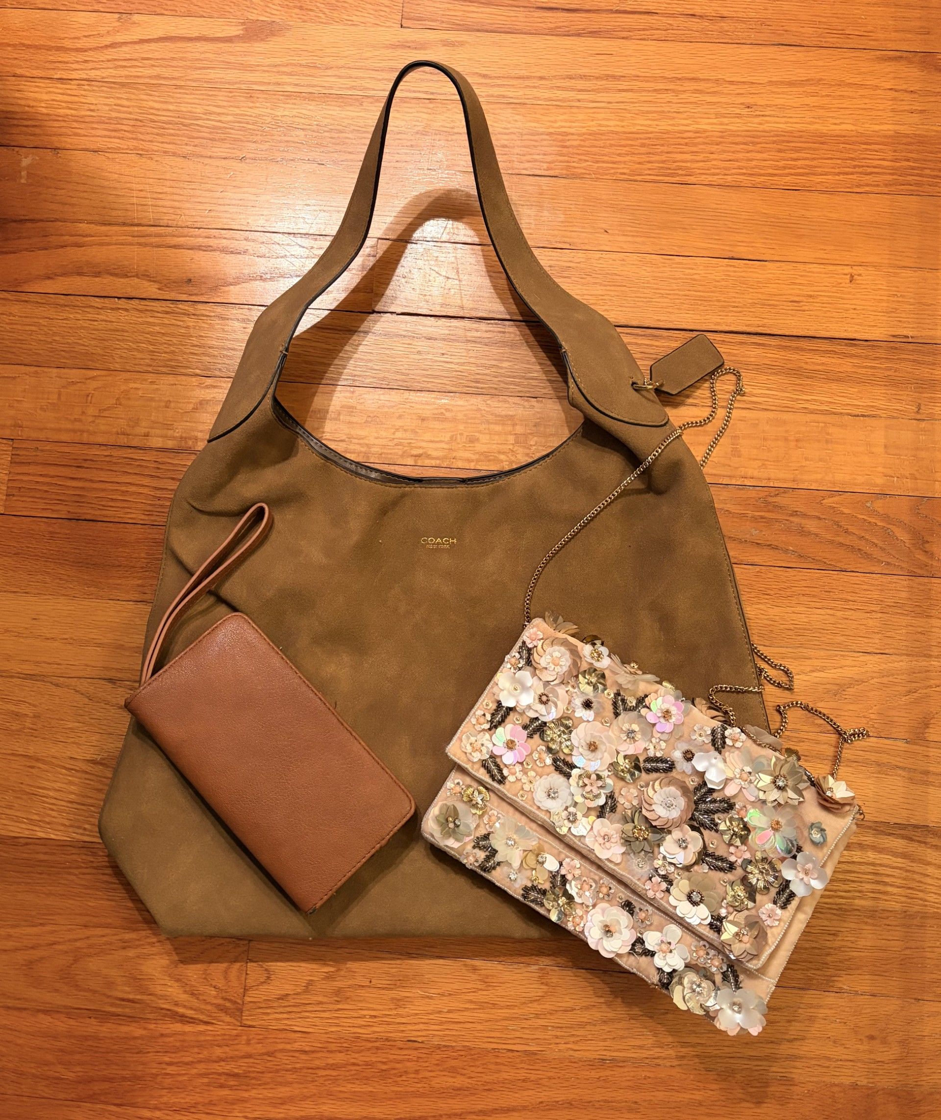 Brown shoulder bag with two small pouches, one tan and one floral, on a wooden surface