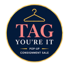Navy circular logo with gold hanger and pink text: “TAG YOU’RE IT” pop-up consignment sale