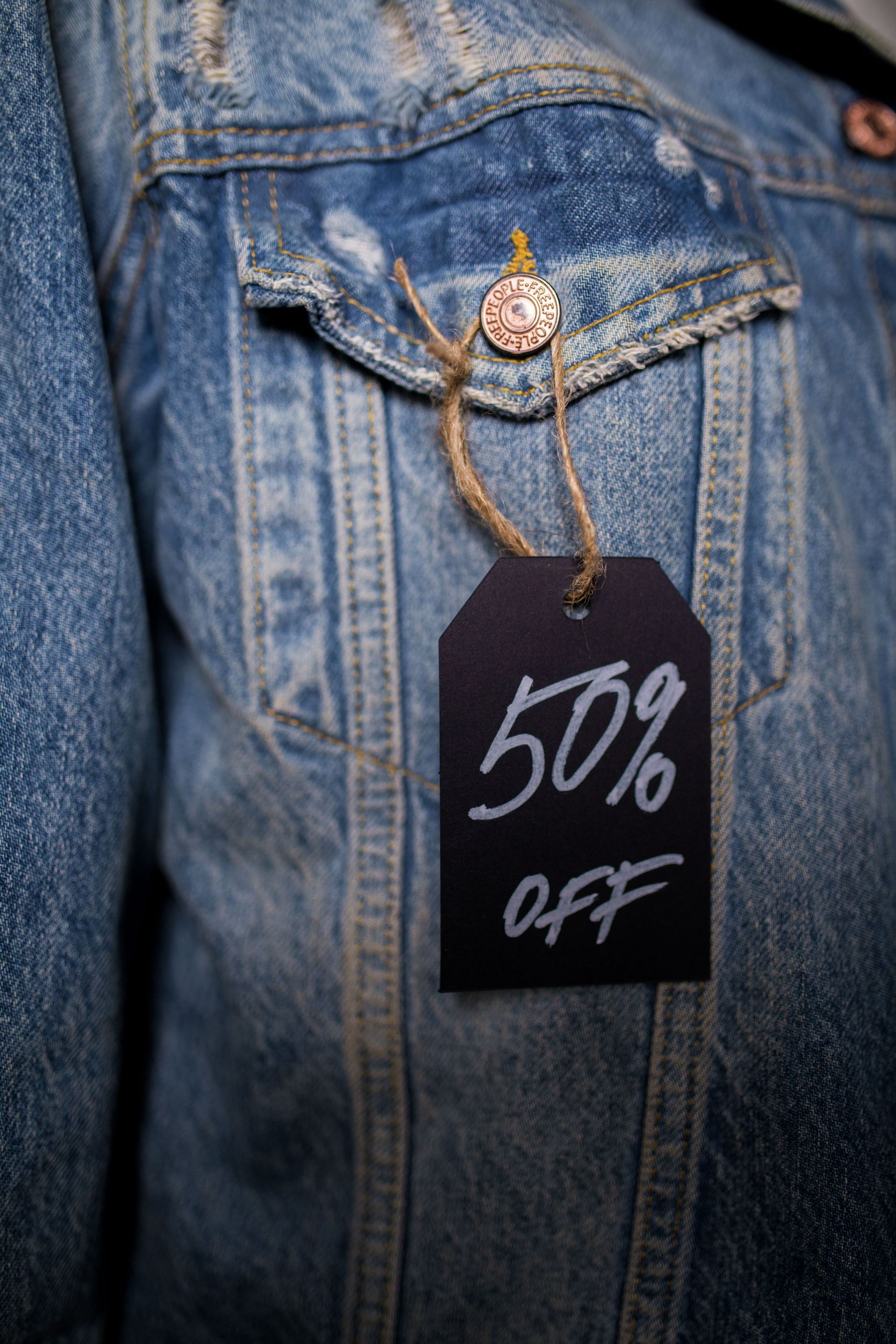 Denim jacket with a hanging tag reading “50% OFF”