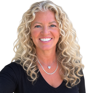 Smiling woman with long curly blonde hair wearing a black top and silver necklace against a white background