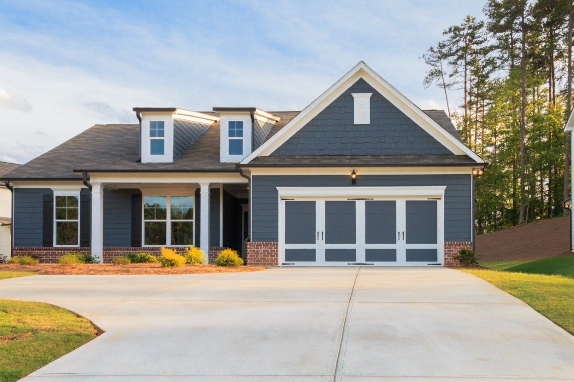 Suburban house with gray siding, a two-car garage, and a wide concrete driveway