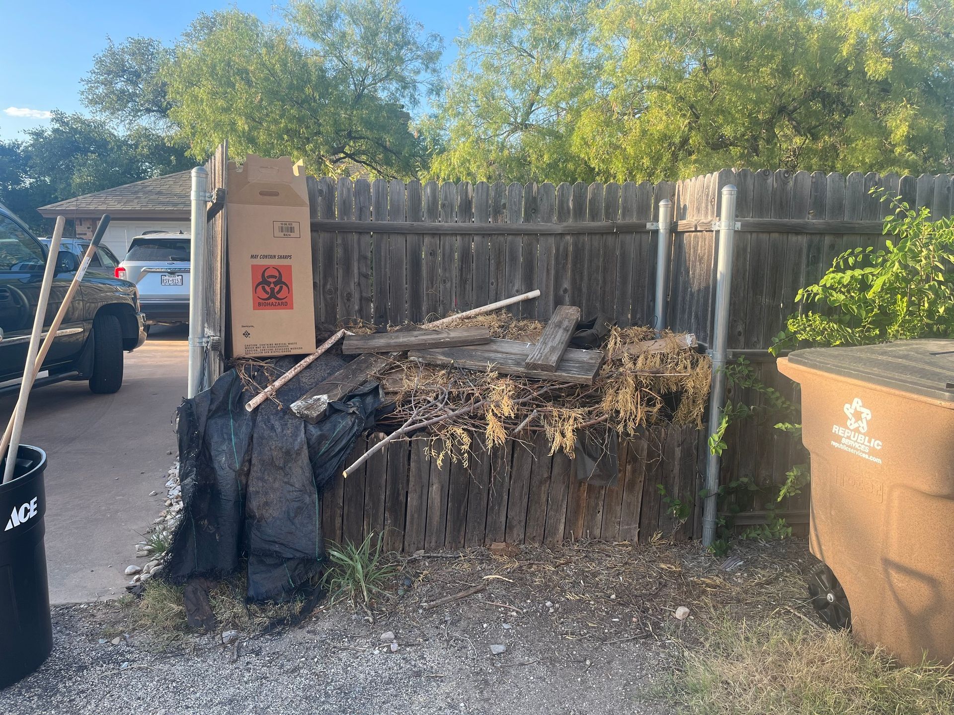 A pile of trash is sitting in front of a wooden fence.