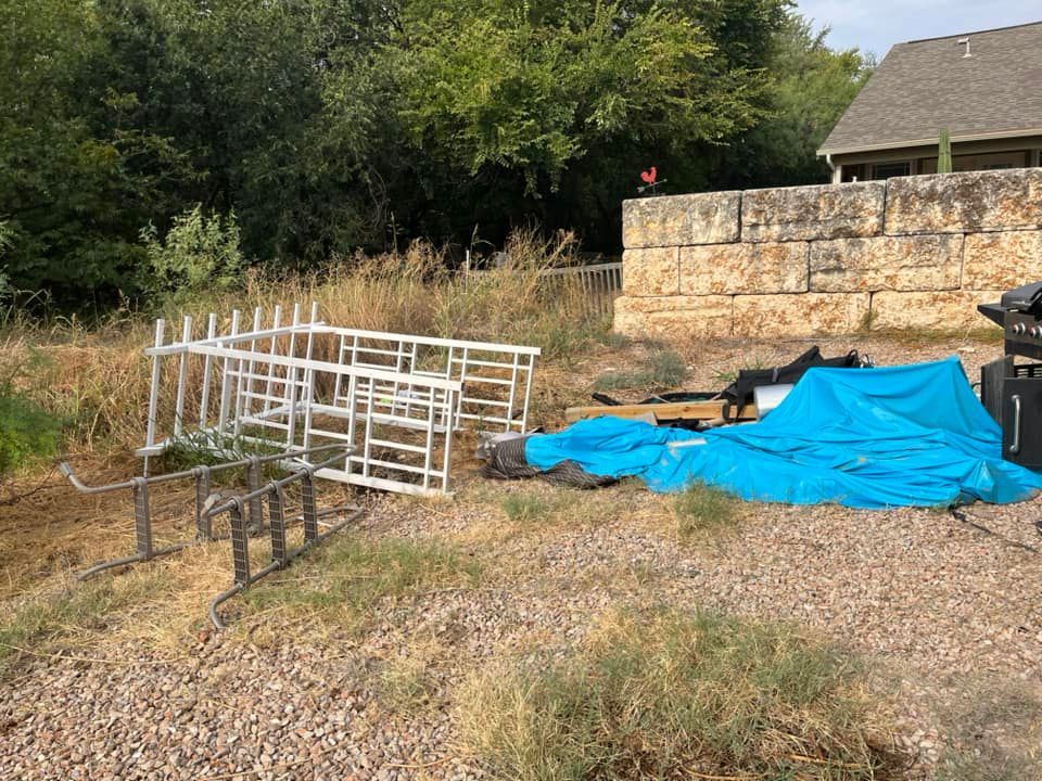 A pile of junk is sitting on the ground in front of a stone wall.