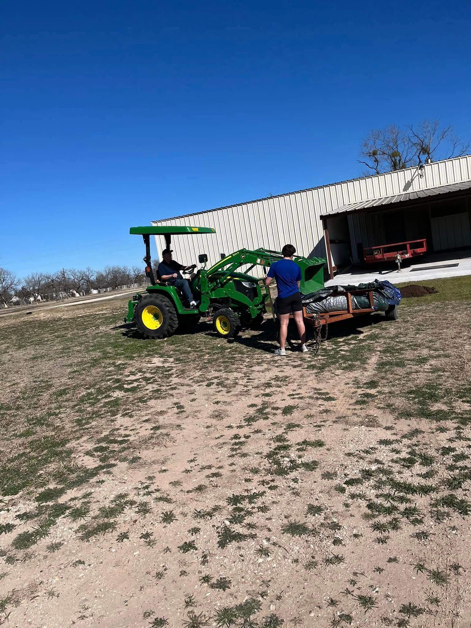 A man is standing next to a green tractor in a field.