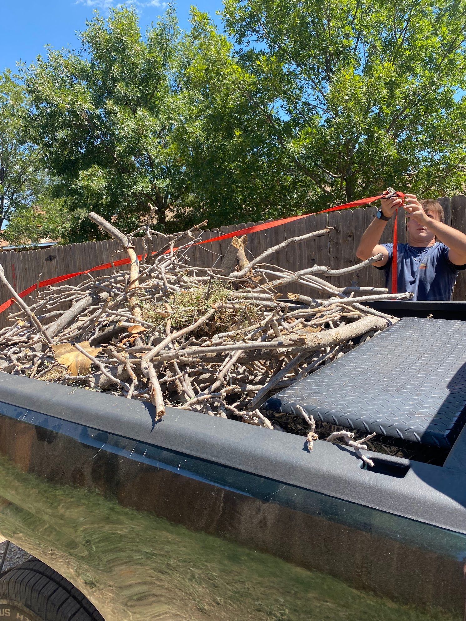 A person is standing in the back of a truck holding a rope.