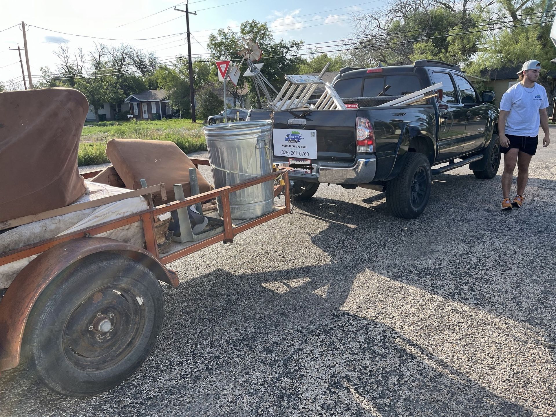 A man is standing next to a truck with a trailer attached to it.