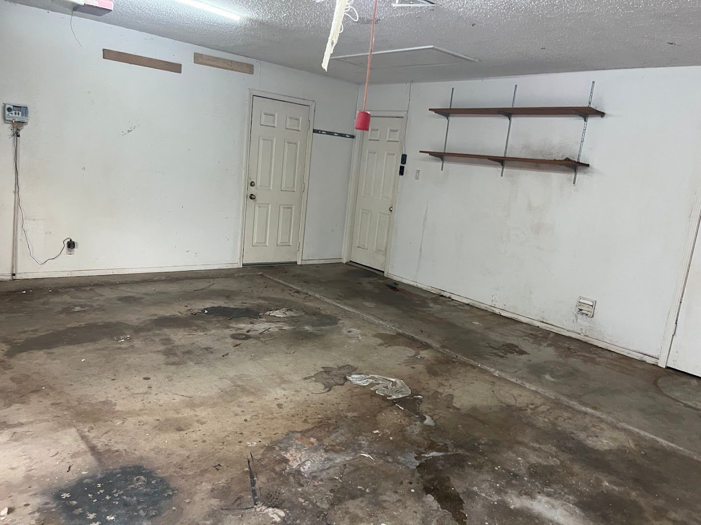An empty garage with a dirty floor and white walls.