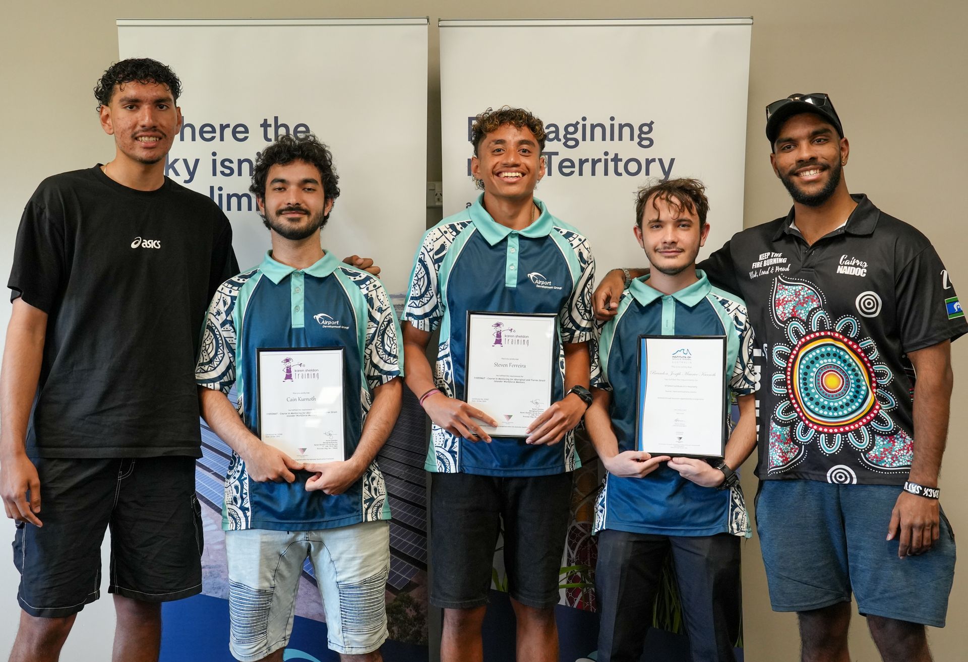 Five men in a room, holding awards, smiling. They are in front of a banner with words 