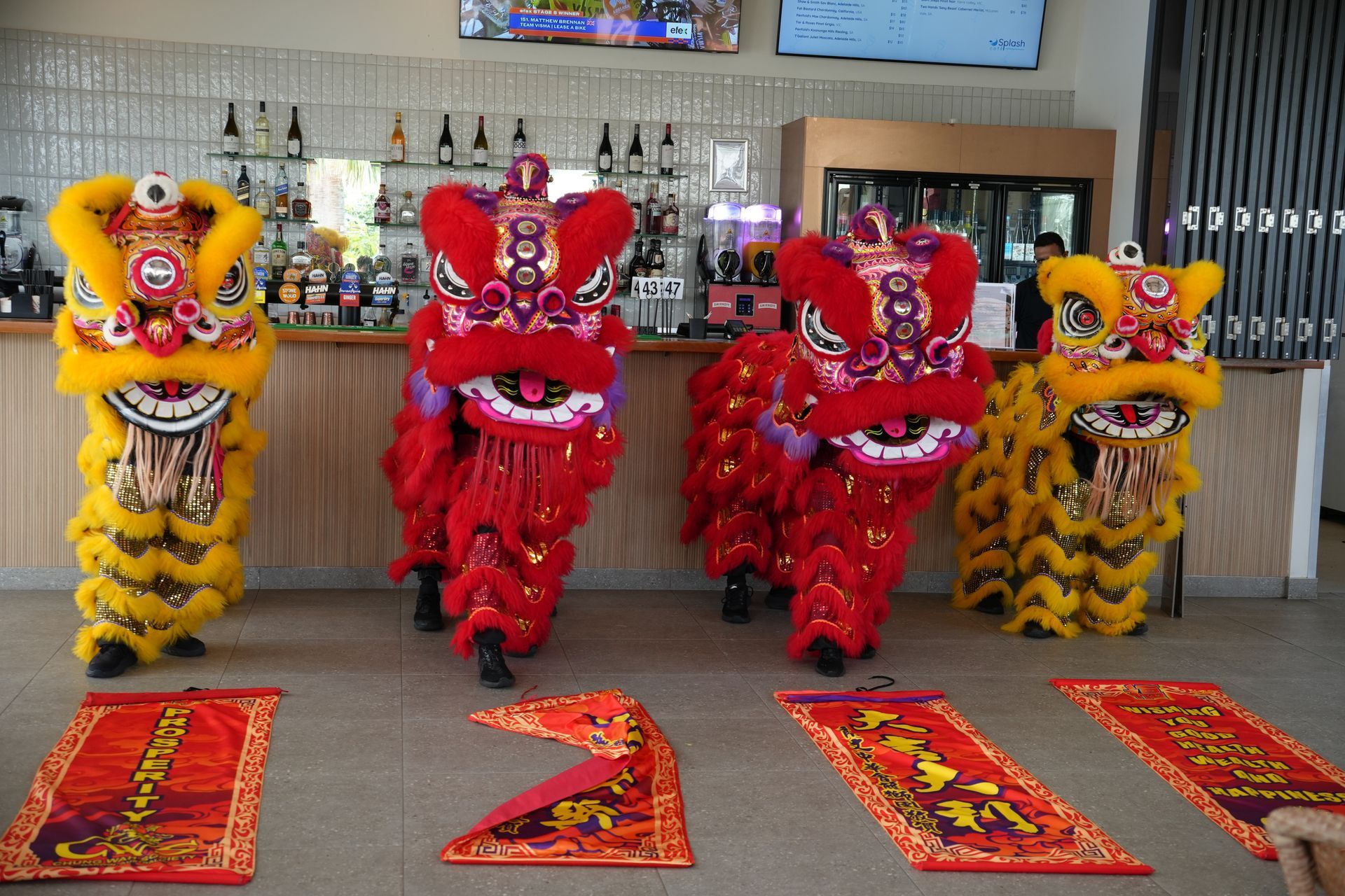 Four colorful lion dance costumes stand before a bar.