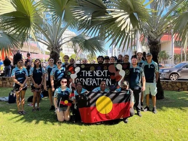 Group of people holding Aboriginal flag, banner reading