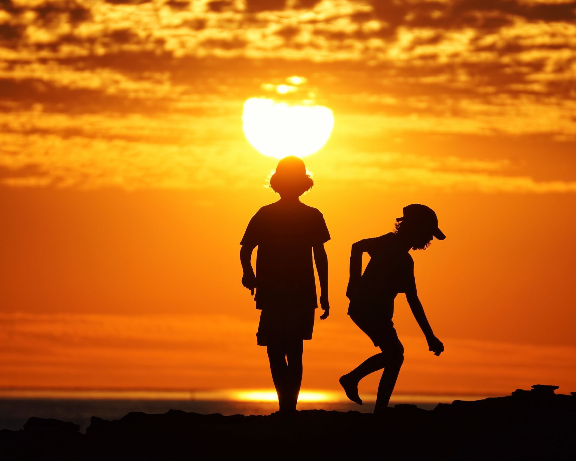 A silhouette of two kids playing during sunset.