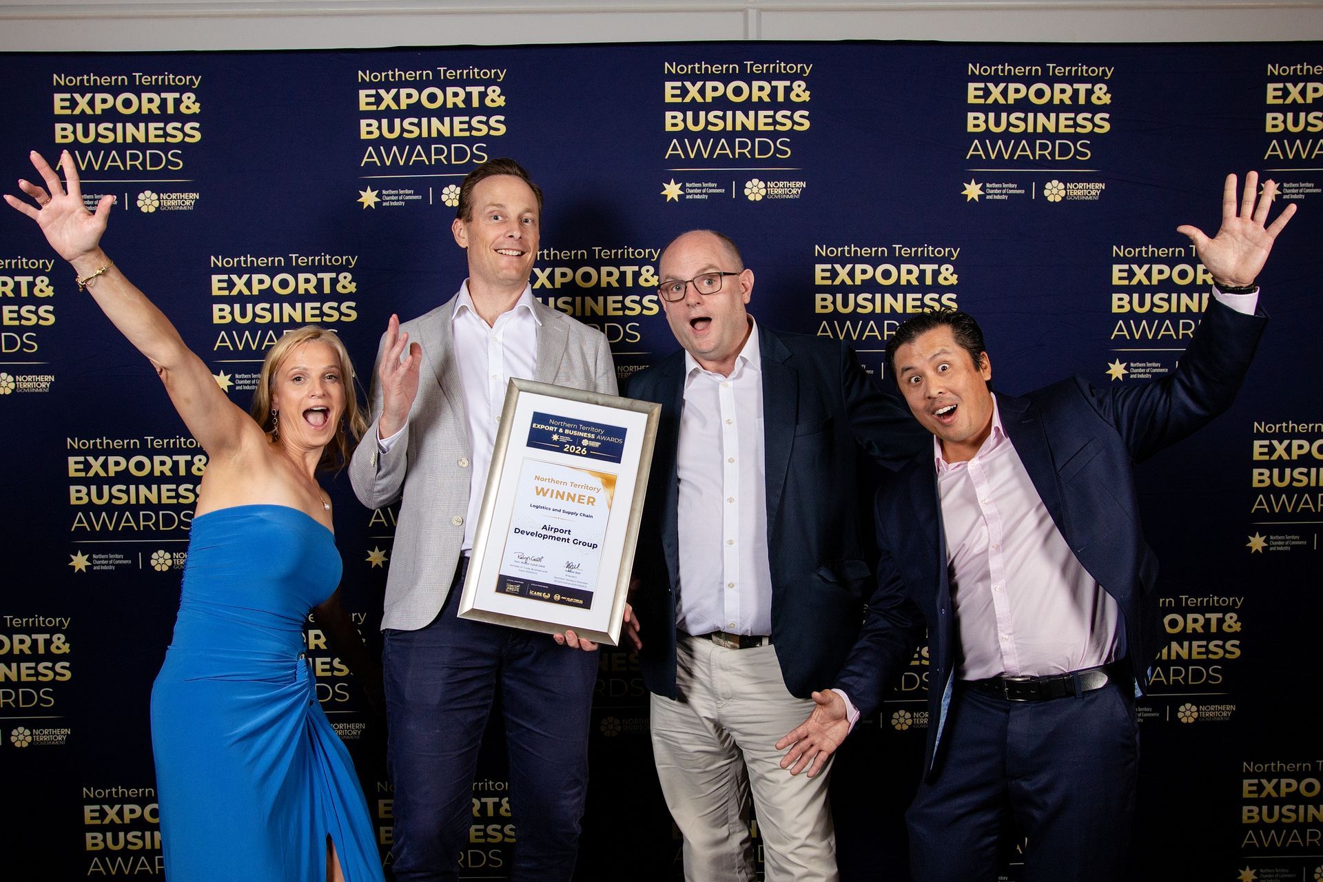 Four people posing with an award plaque at the Exports Business Awards backdrop, smiling and celebrating.