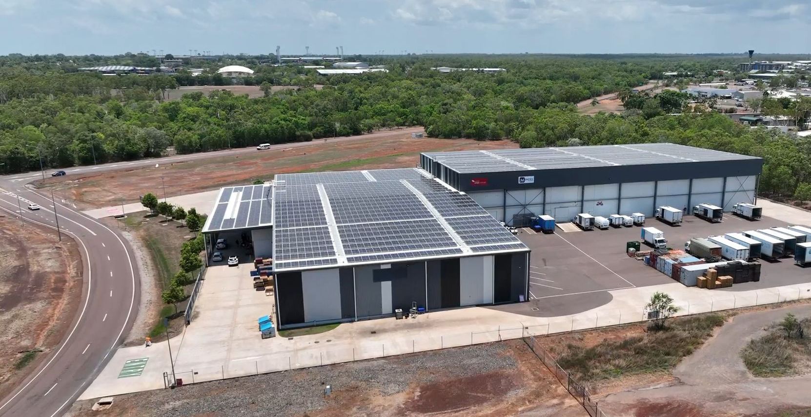 An aerial footage of a warehouse with solar panels on its roof.