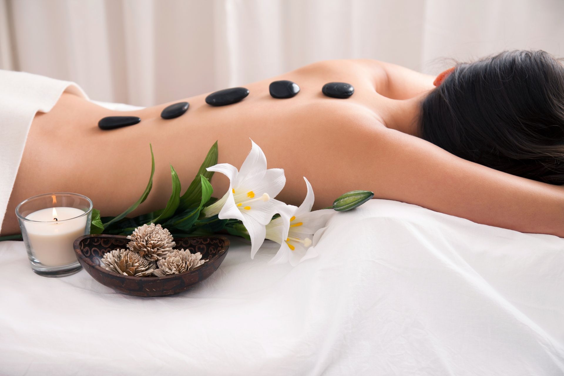 A woman is getting a massage with hot rocks on her back.