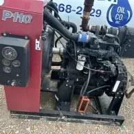 A red P110 industrial pump unit with an exposed black diesel engine, control gauges, and pipes, set on a gravel surface.
