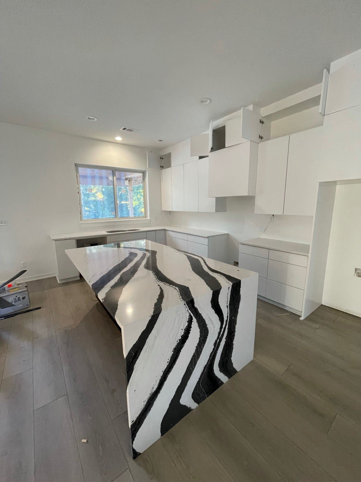 Modern white kitchen with zebra-striped island countertop and light gray flooring.