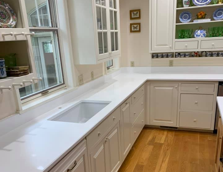 White kitchen with cabinets, countertops, and a sink; hardwood floor.