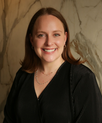 Smiling person in a black top before a marble wall background