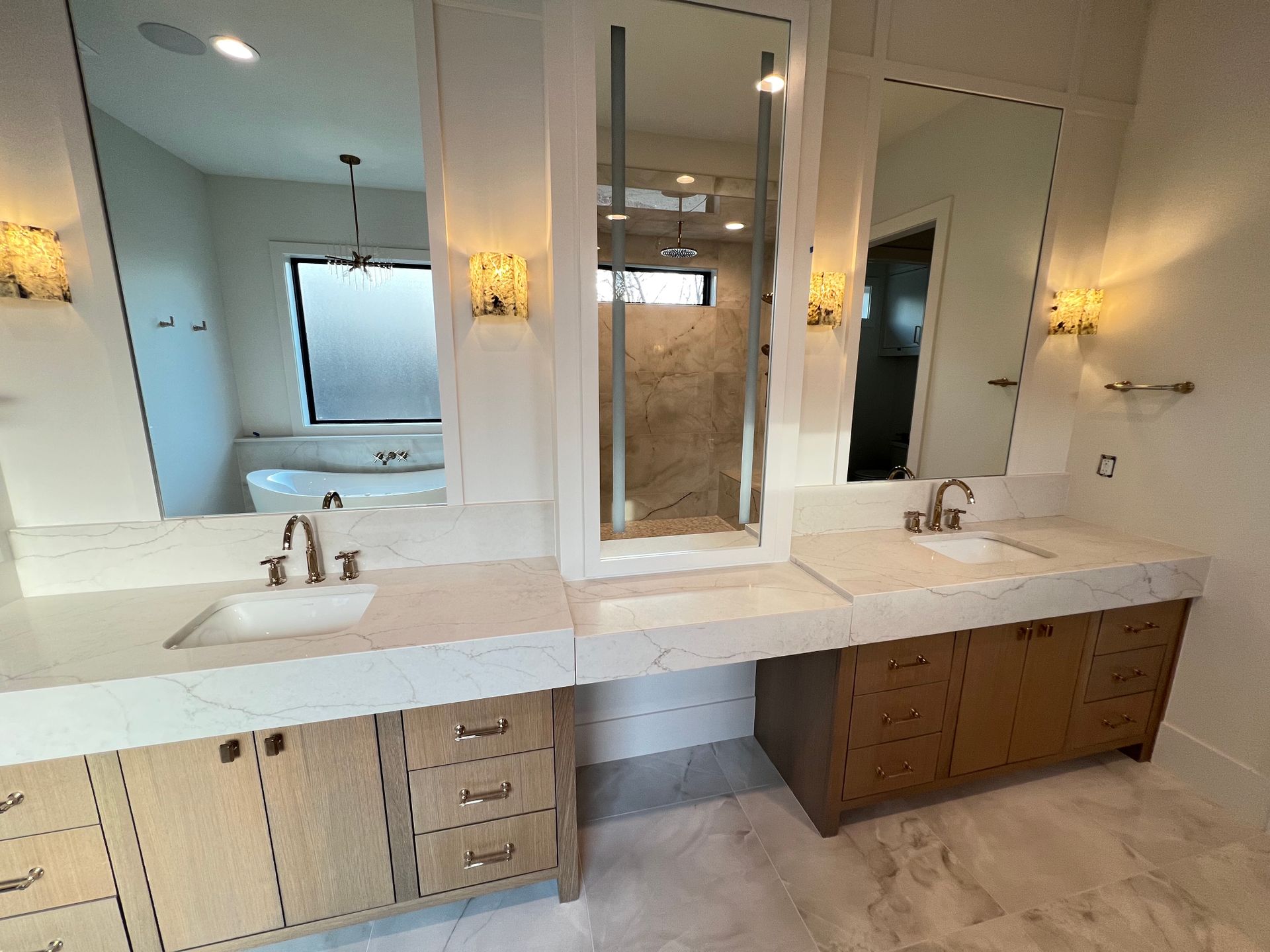 Bathroom with double sinks, large mirrors, and light wood cabinets.