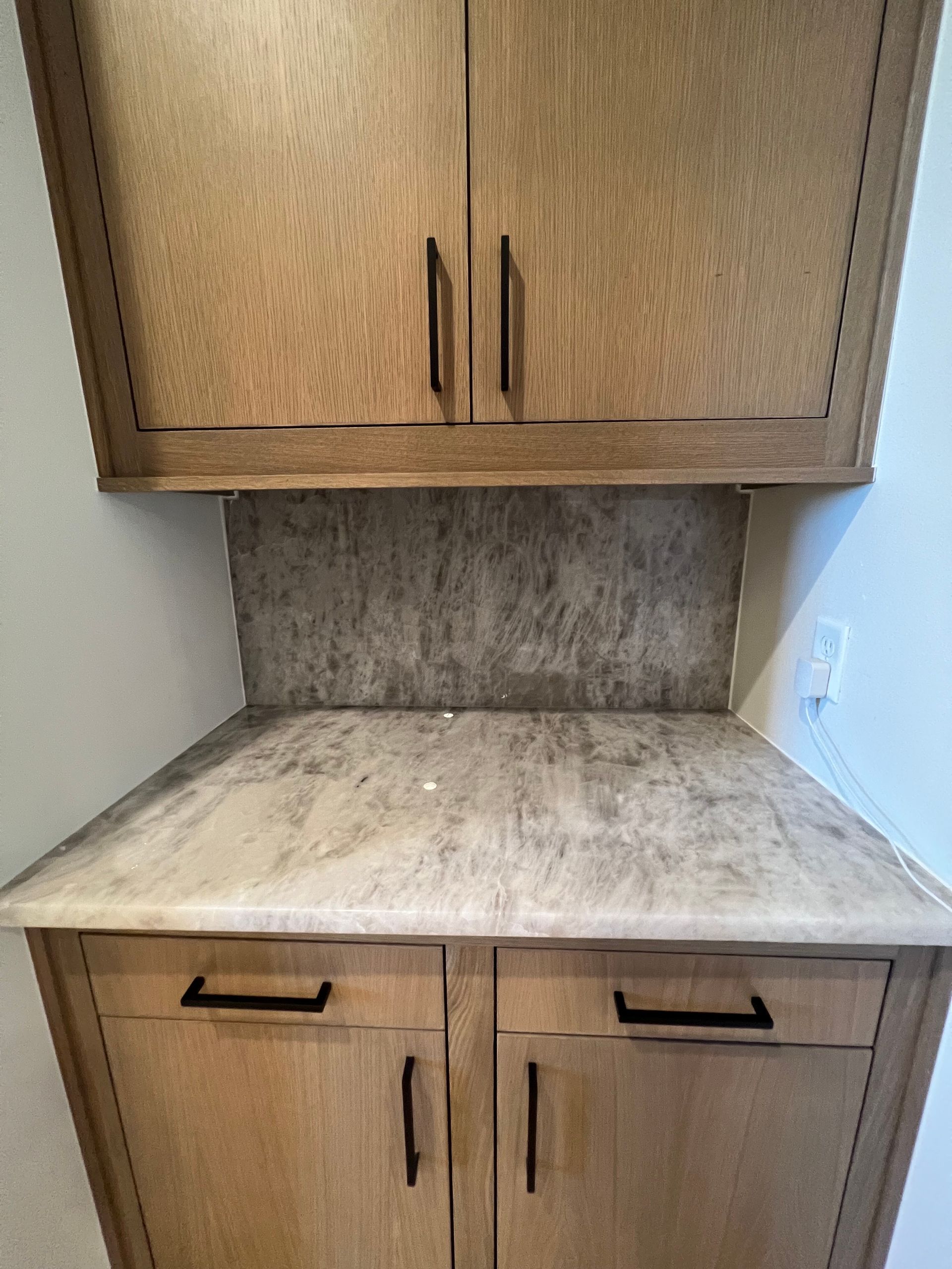Oak kitchen cabinets with gray countertops and backsplash.