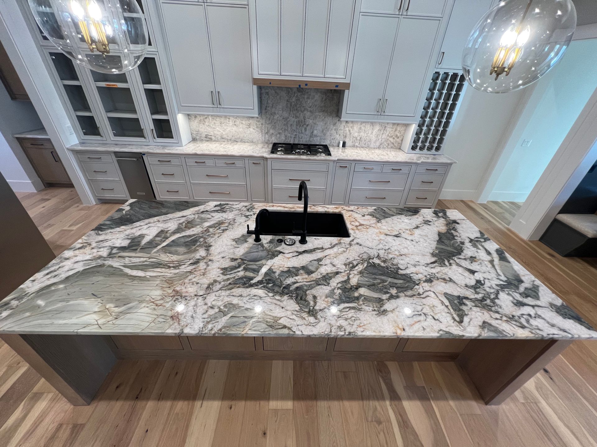 Modern kitchen with white cabinets, granite countertop island, and hardwood floors.