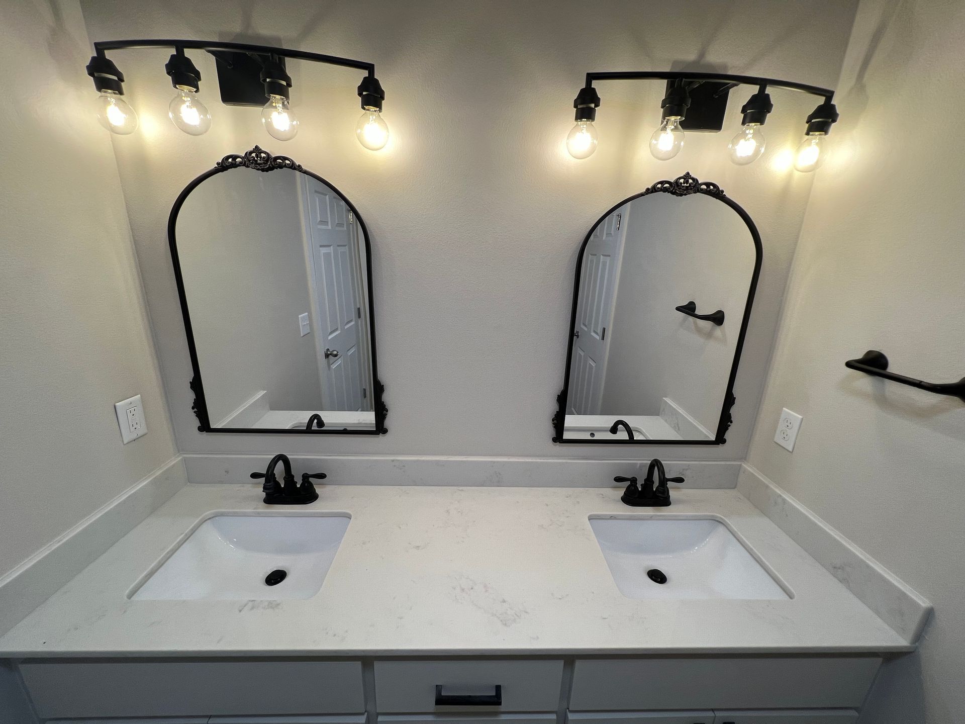 Bathroom with dual sinks, mirrors, and black fixtures.