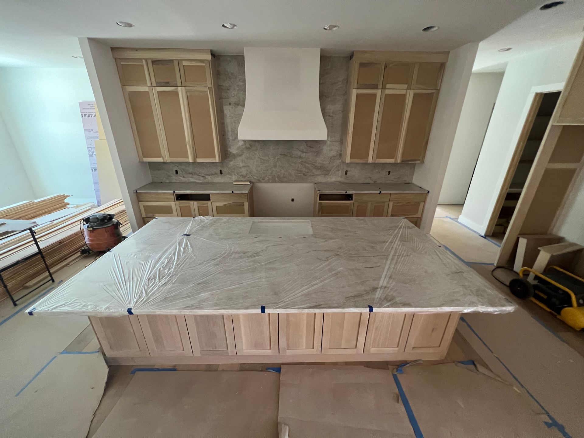 Kitchen renovation in progress, featuring unfinished cabinets, granite countertops, and an island.