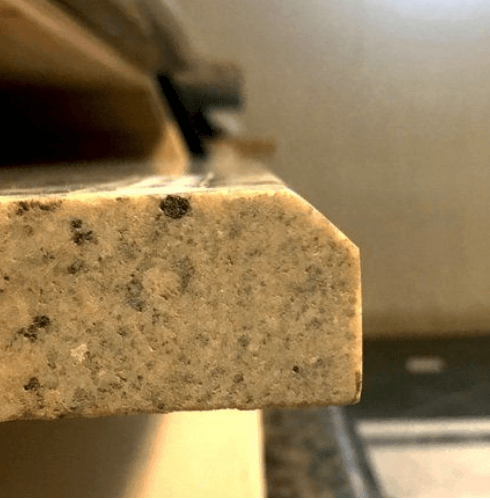 Close-up of a granite countertop edge with a rounded corner.