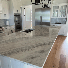 Kitchen with white cabinets, stainless steel appliances, and a large marble countertop.