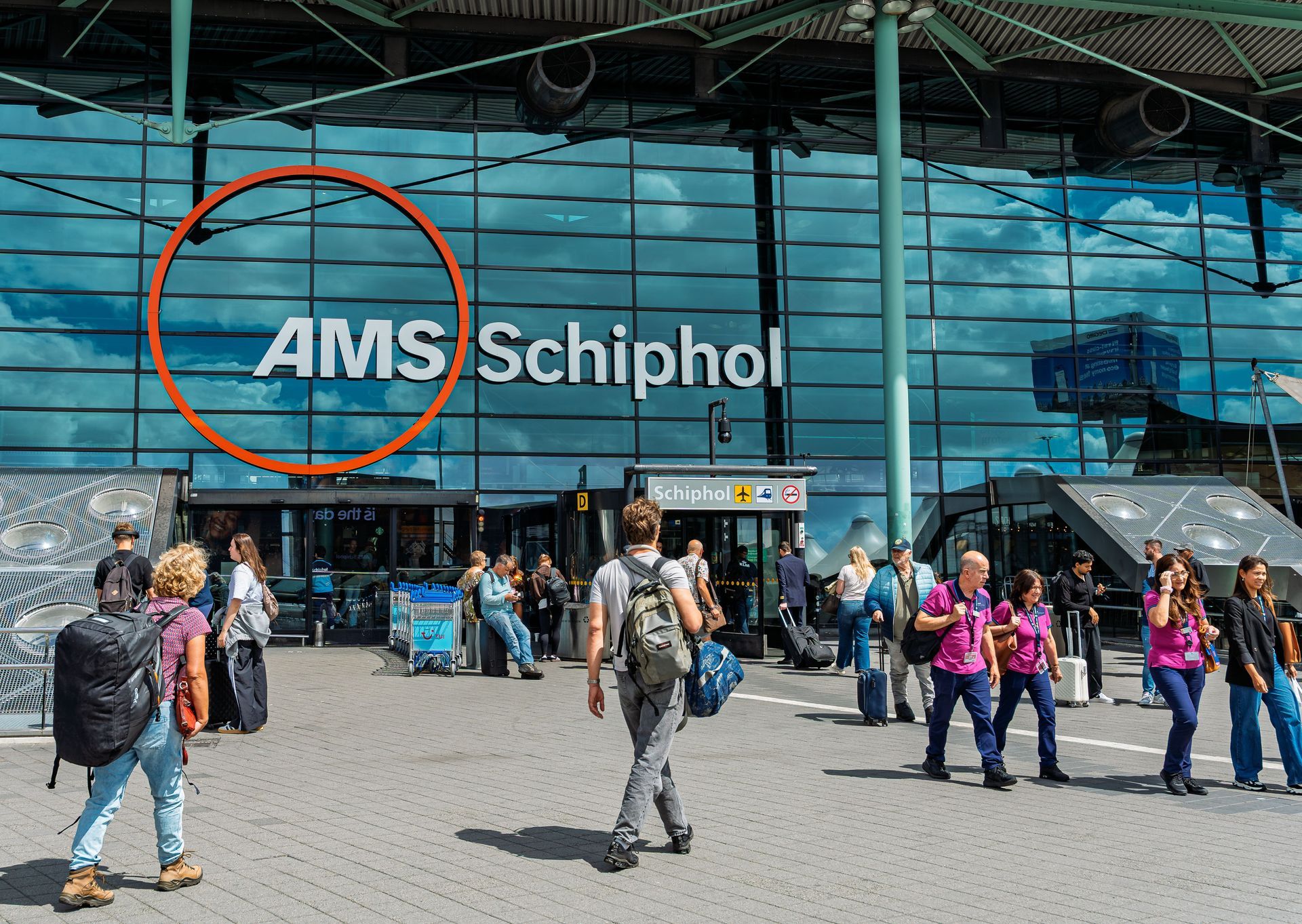 A group of people are standing outside of a building at an airport.