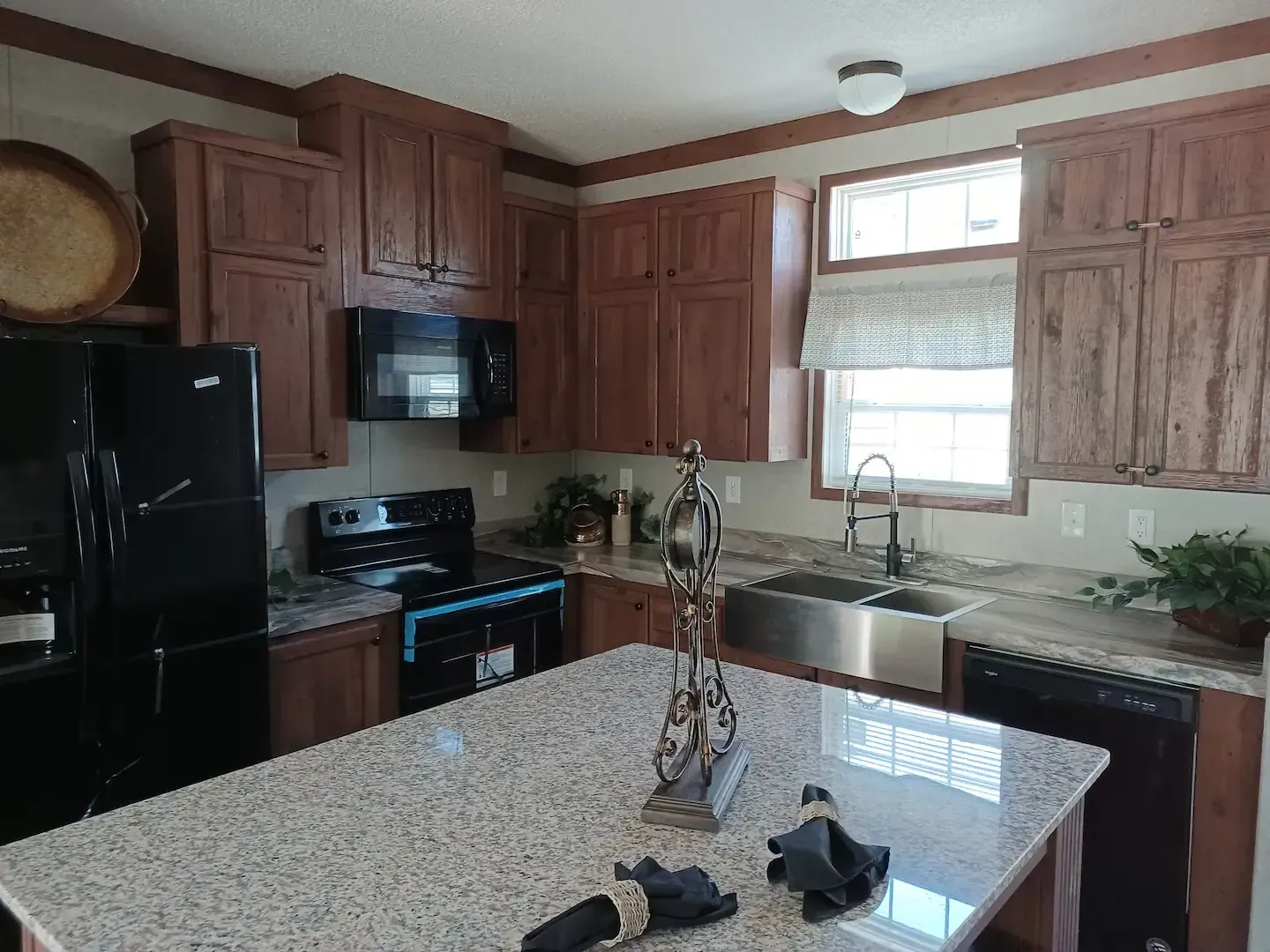 Kitchen with wooden cabinets, granite countertops, and black appliances.