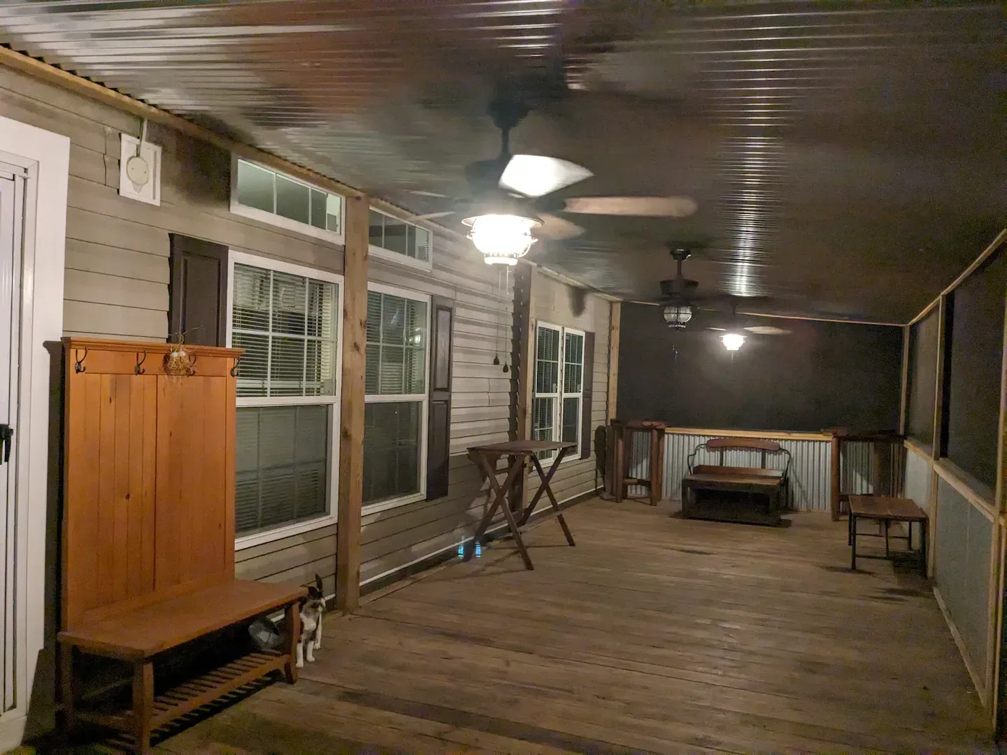 Enclosed porch with wooden floor and ceiling, several ceiling fans, and wooden furniture.