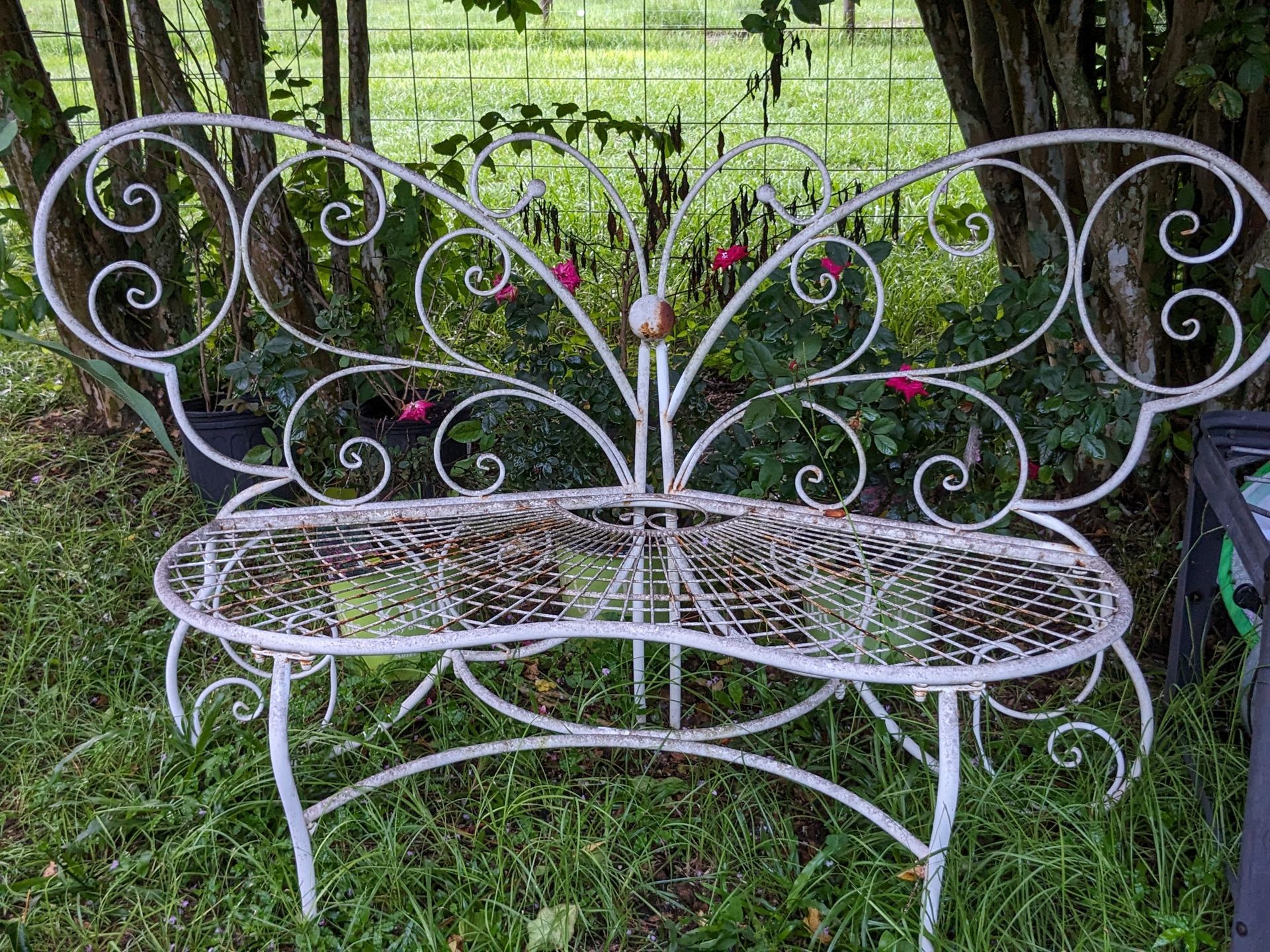 White metal butterfly bench in a garden.