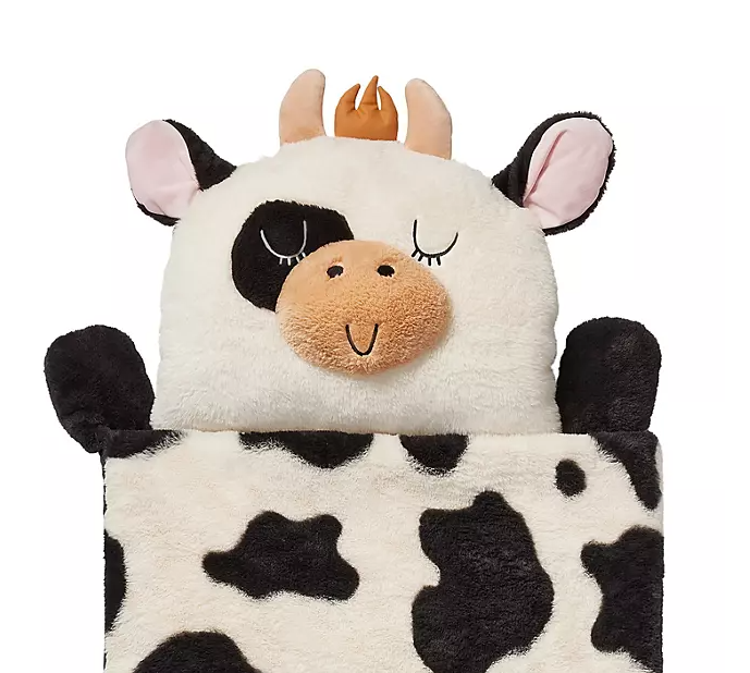Fluffy cow plushie with a crown, black and white spotted blanket.