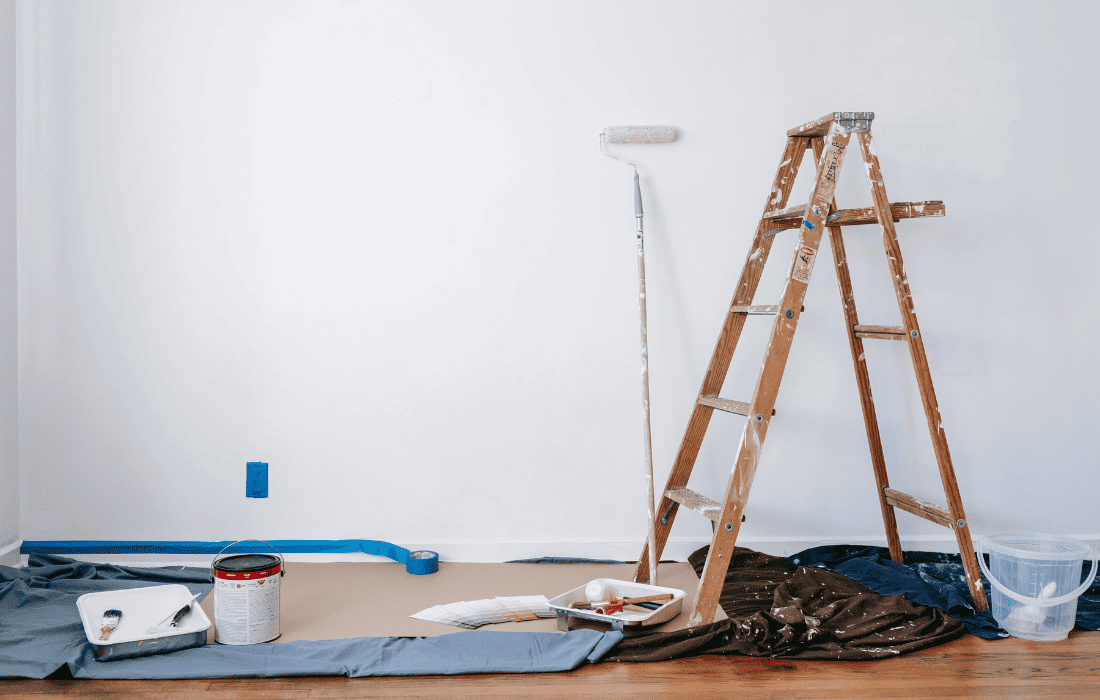 Step ladder, paint roller, and paint on the ground, in the middle of an interior paint job