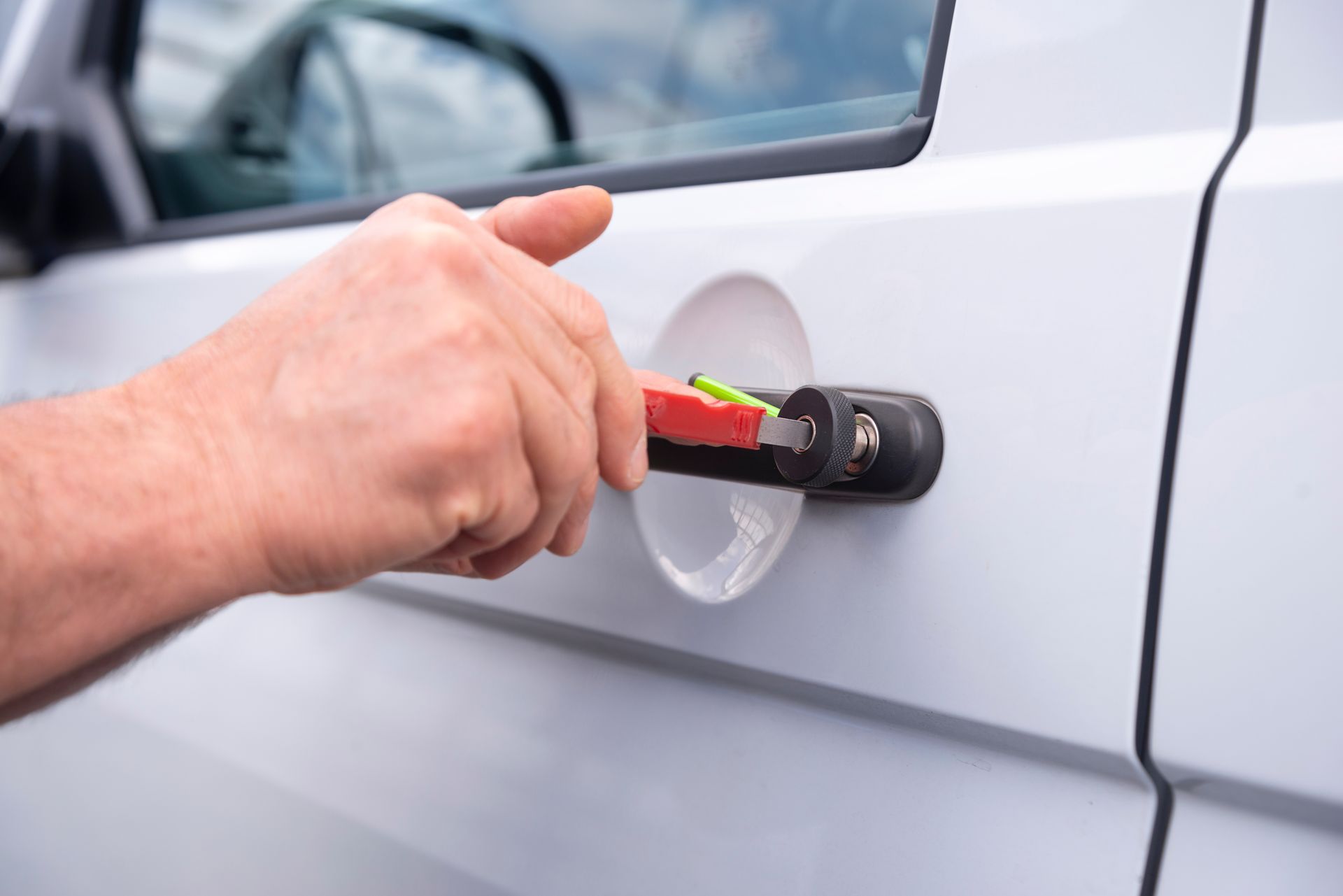 A person is opening the door of a white van with a wrench.
