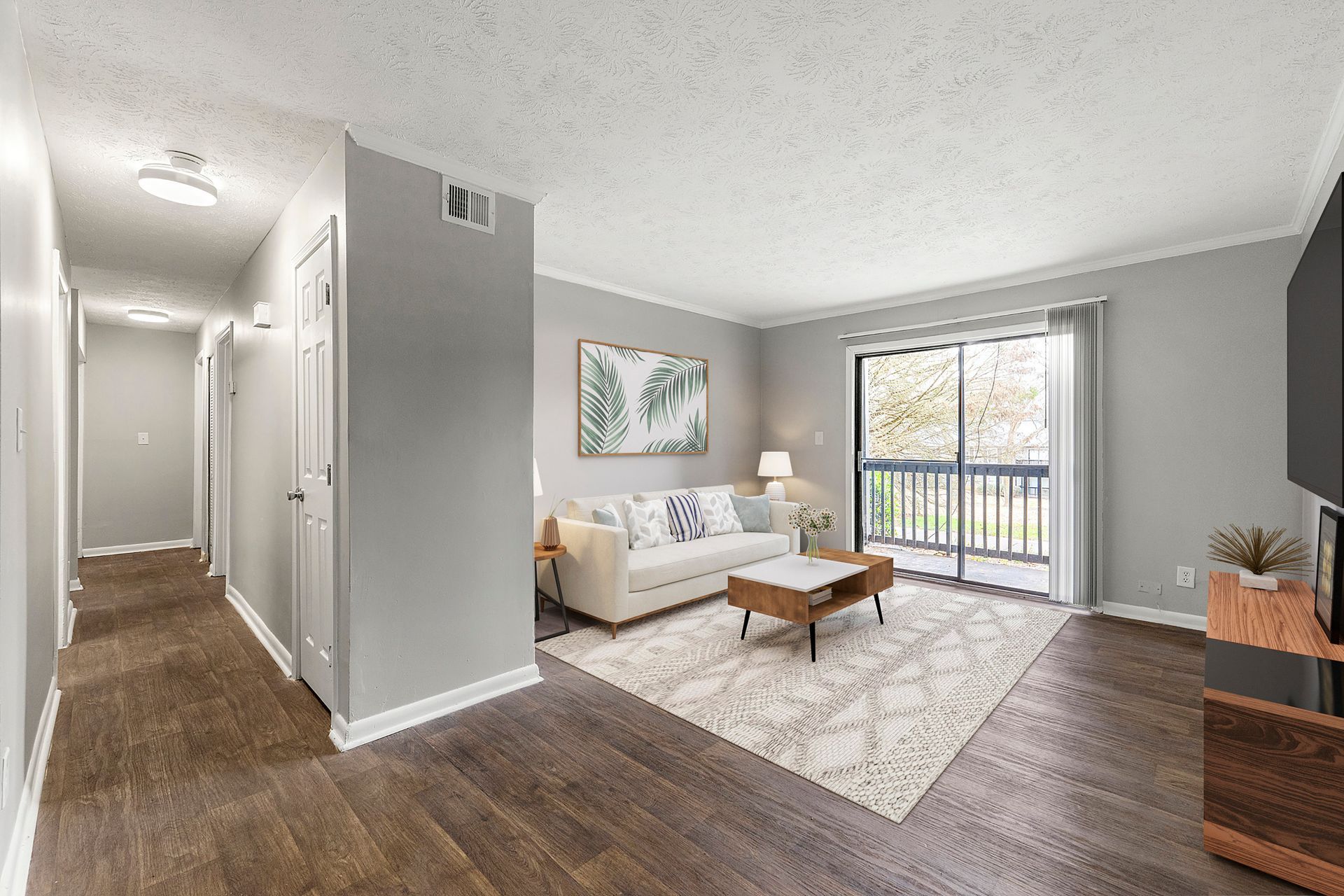 Modern apartment living room with white sofa, coffee table, gray walls, and sliding glass door to balcony