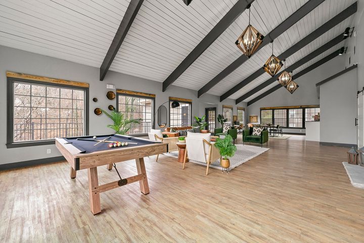 Spacious open living area with pool table, vaulted ceiling, and large windows
