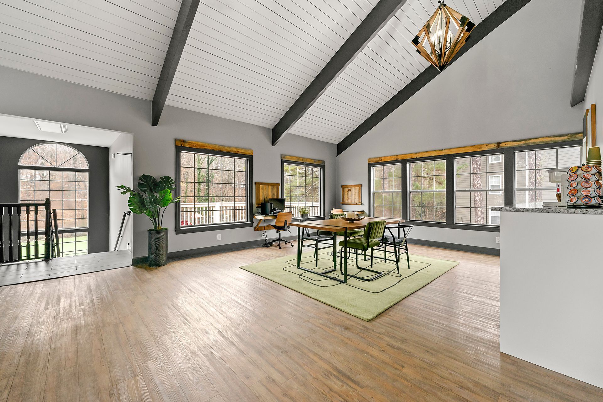 Bright airy loft dining room with large windows, wooden floor, and a table on a green rug