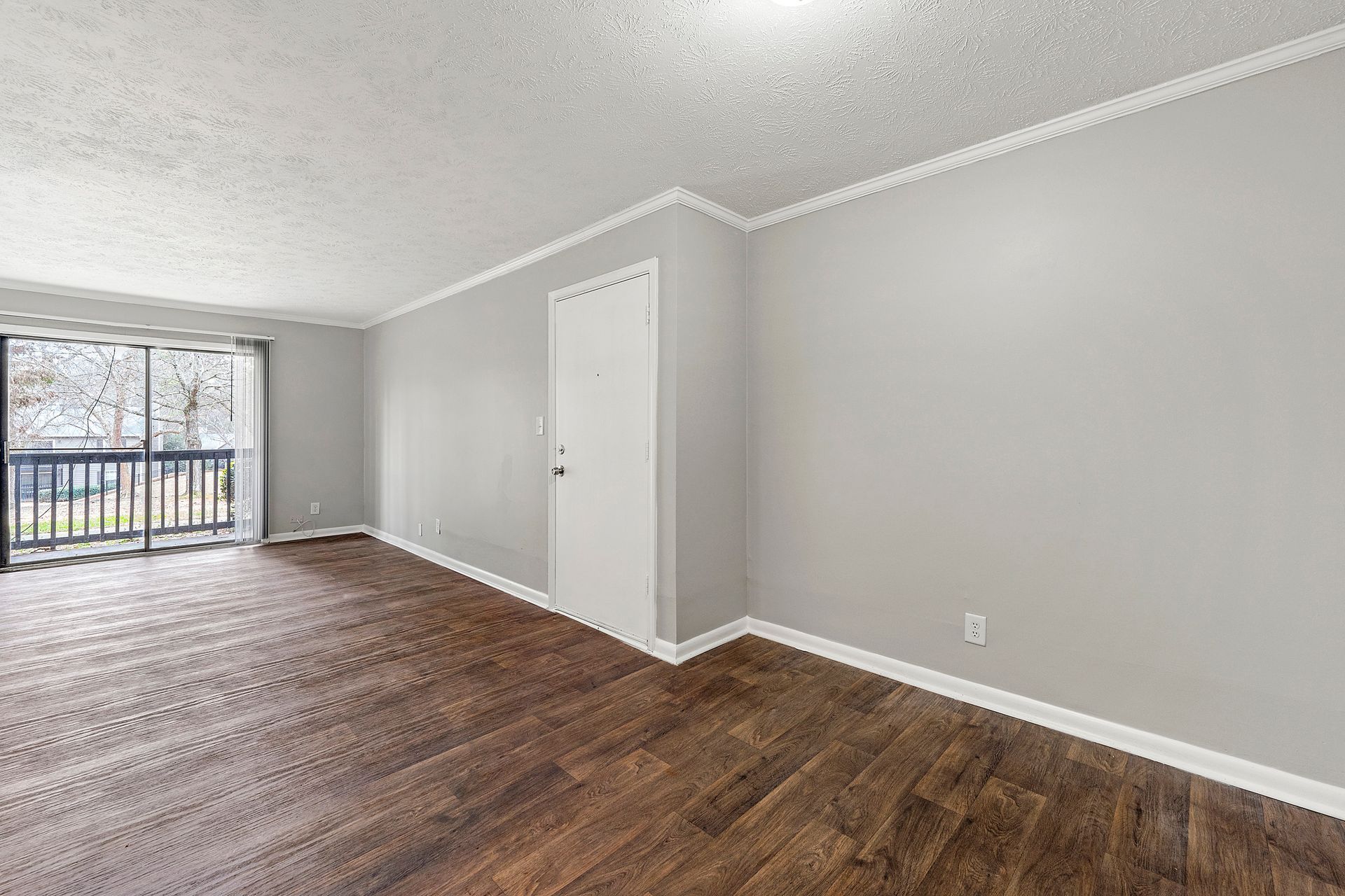 Empty gray room with wood floors and sliding glass door to a balcony