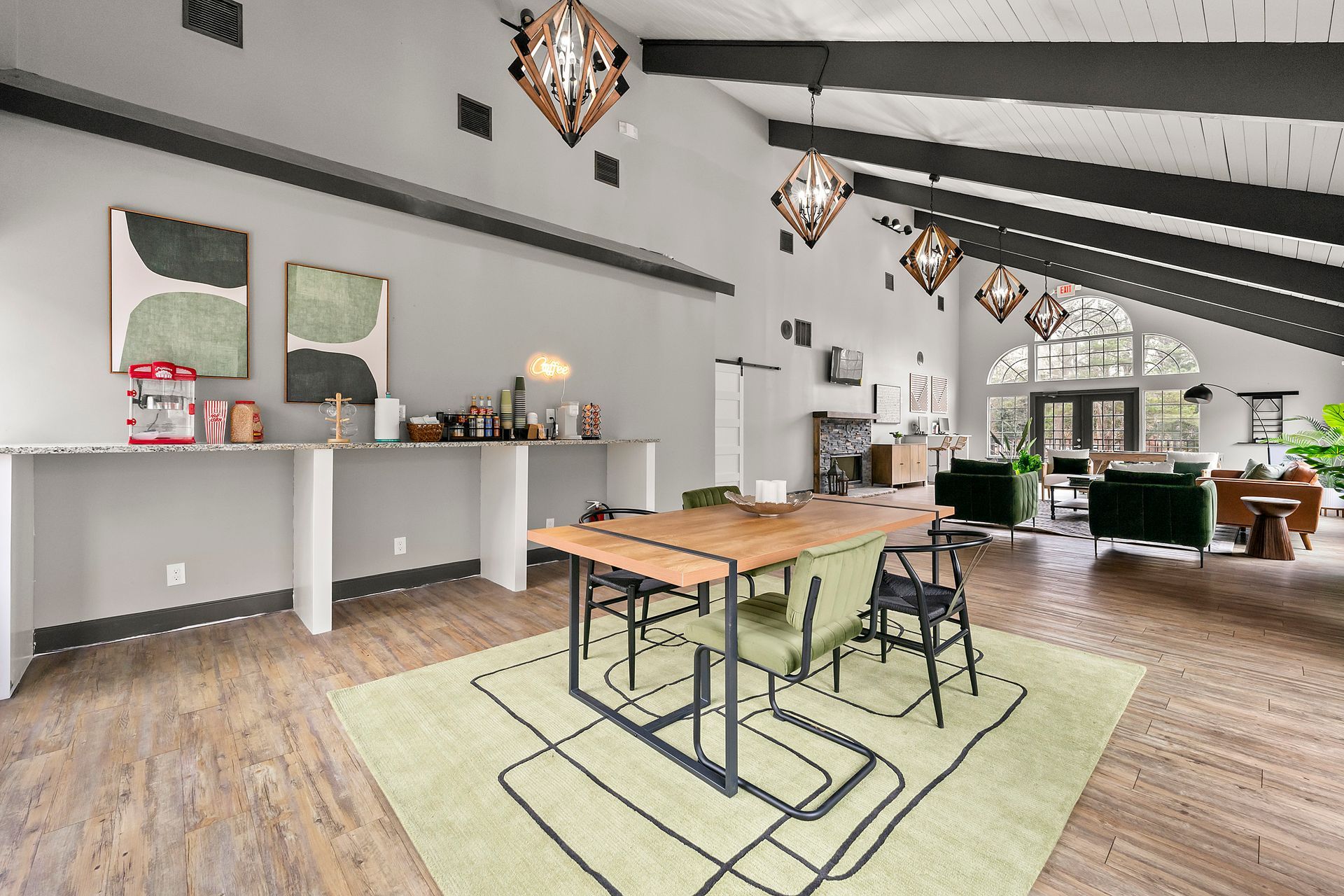 Modern loft-style living space with dining table, sofas, high ceilings, and hanging pendant lights.