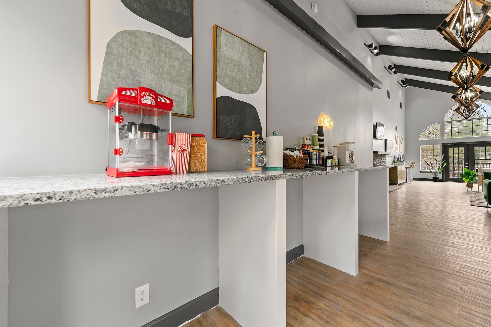 Modern breakfast bar with granite counter, coffee station, and pendant lights in a bright hallway