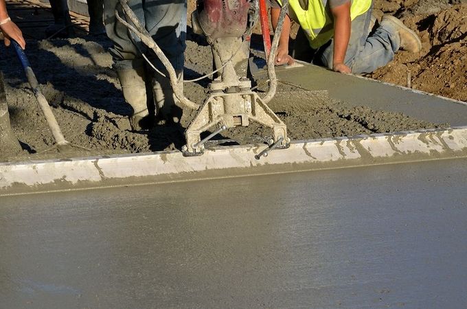 A group of construction workers are working on a concrete floor