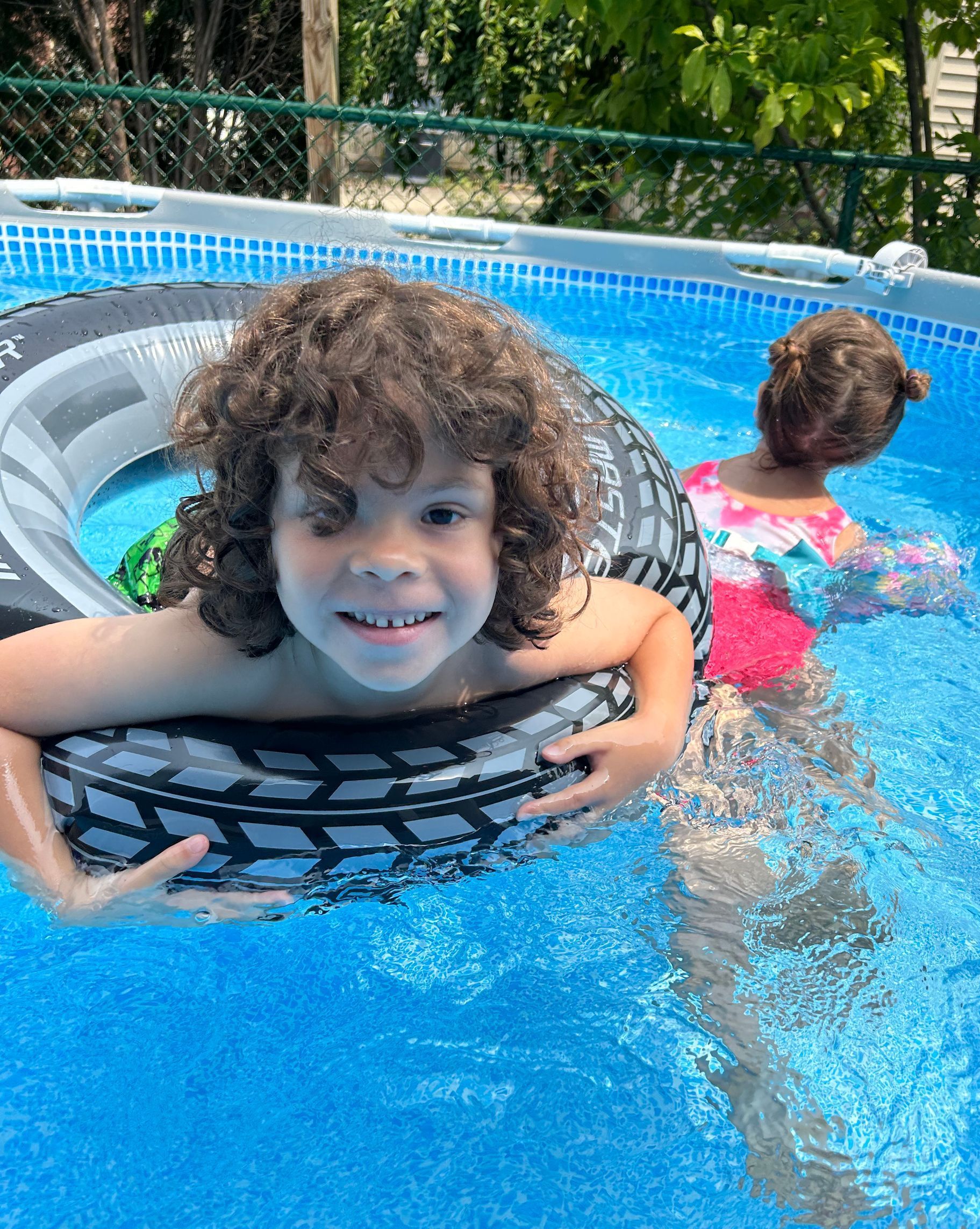 Child floating in inflatable tube in an above ground swimming pool.