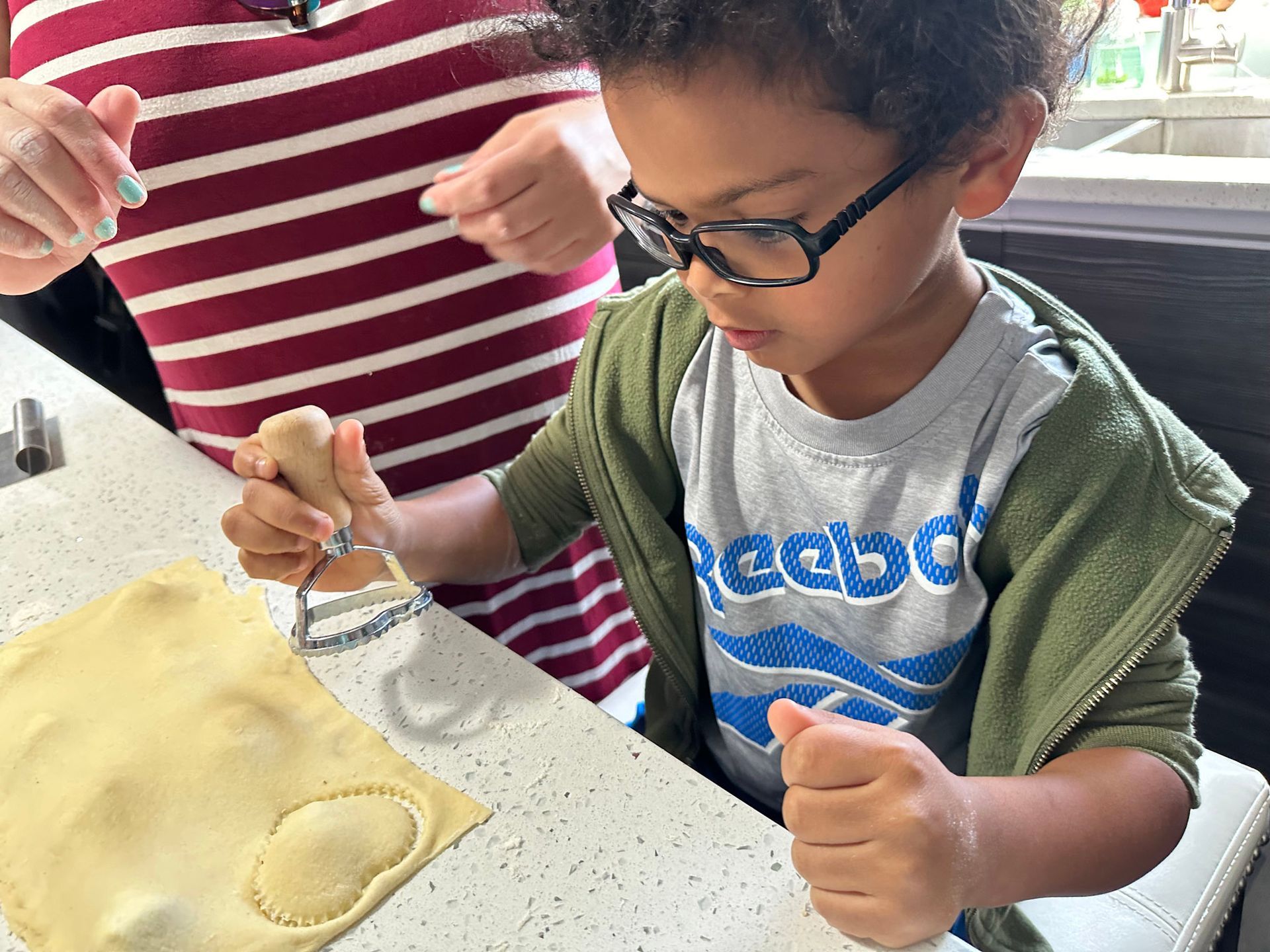 child using cookie cutter to make a ravioli shape