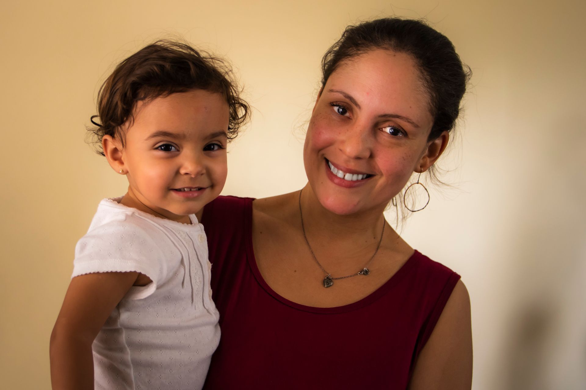 Smiling teacher holding a smiling toddler.